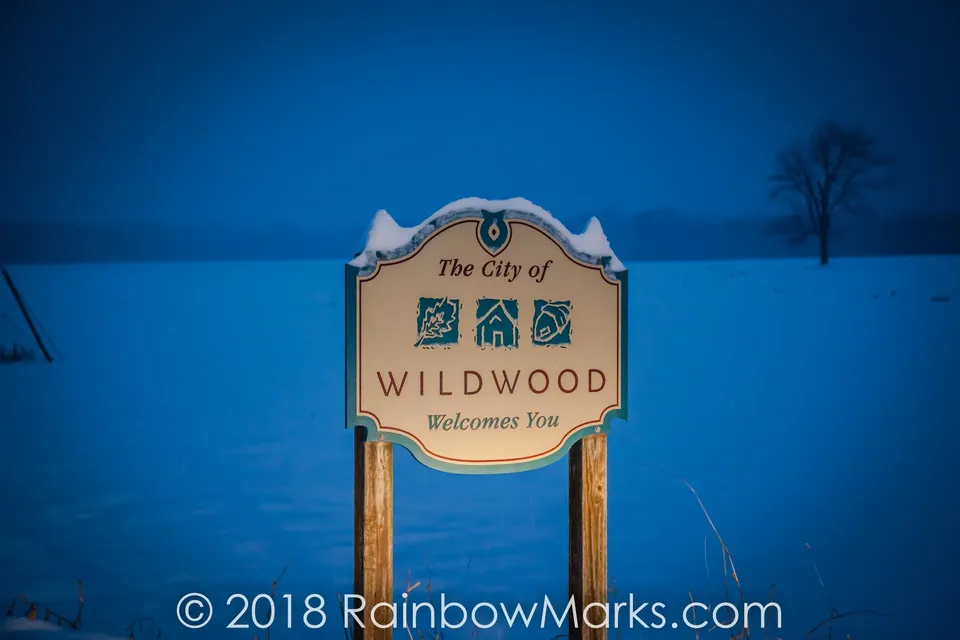 The City of Wildwood welcome sign in a snowy field at dusk